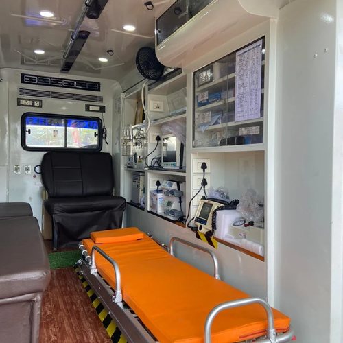 Inside SSR ICU ambulance cabin with orange stretcher trolley, attendant seat and medical supply cabinet